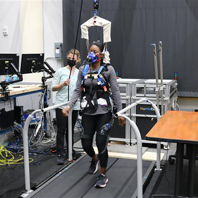female wearing an exoskeleton with a female researcher standing beside her
