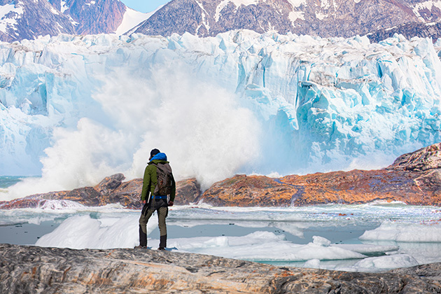 hiker observing melting glaciers in Greenland