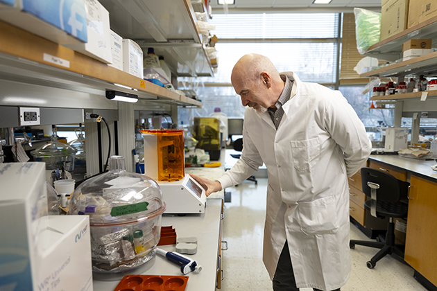 male researcher working in a lab and looking at a heart valve prototype inside a heart simulation setup.