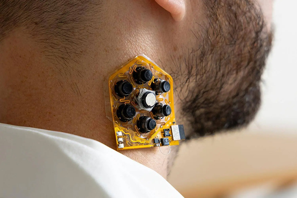 Wearable experimental device with multiple sensors adhered to the side of a person’s neck.