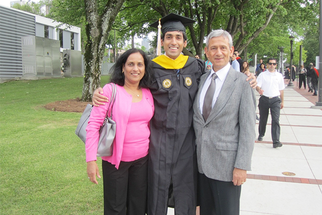 Alex Duncan in a graduation gown standing outside with his parents on either side