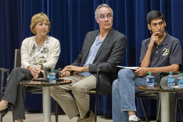 Alex Duncan and two other people sitting in chairs on a stage