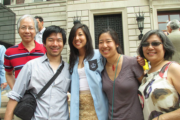 Group of five people, men and women standing in front of a beige building
