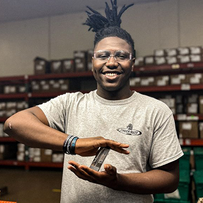 young male researcher standing in a lab holding a piece of equipment