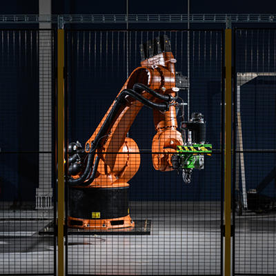 large orange KUKA robot pictured behind a mesh cage