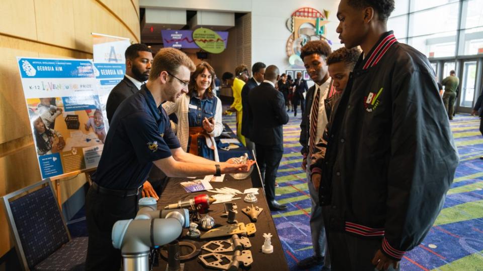Kyle Saleeby, a research engineer with the Georgia Tech Manufacturing Institute, shows visitors how robotics can be used in manufacturing and an array of 3-D printed industrial materials.