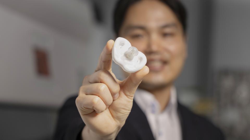 Hong Yeo holding a white pacifier under development at Georgia Tech