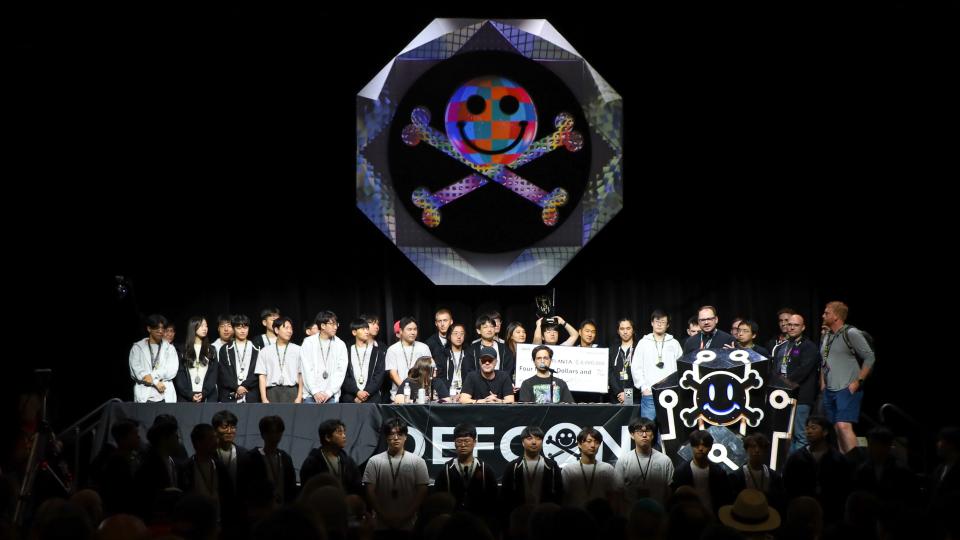 Team Atlanta stands on the dark DefCon stage during the convention's closing ceremony. 