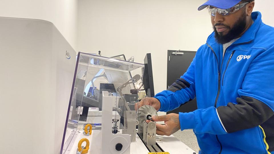 This is a photo of a technician at PBS Aeros space placing a part on a balancing machine in the company's manufacturing facility