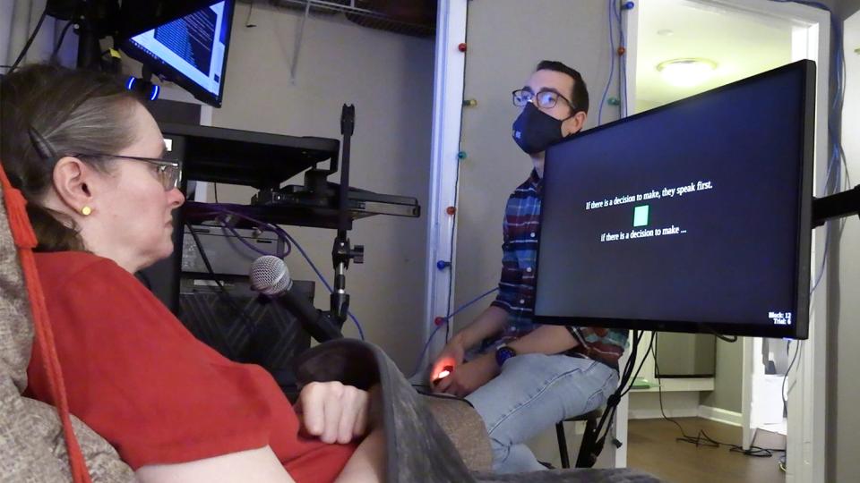 During a research session, a participant looks at a monitor and imagines saying the text cue displayed on screen. Text below the cue shows the brain-computer interface’s prediction of her imagined words.