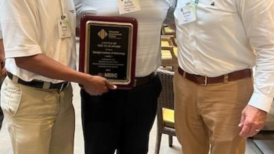 Three men holding an award