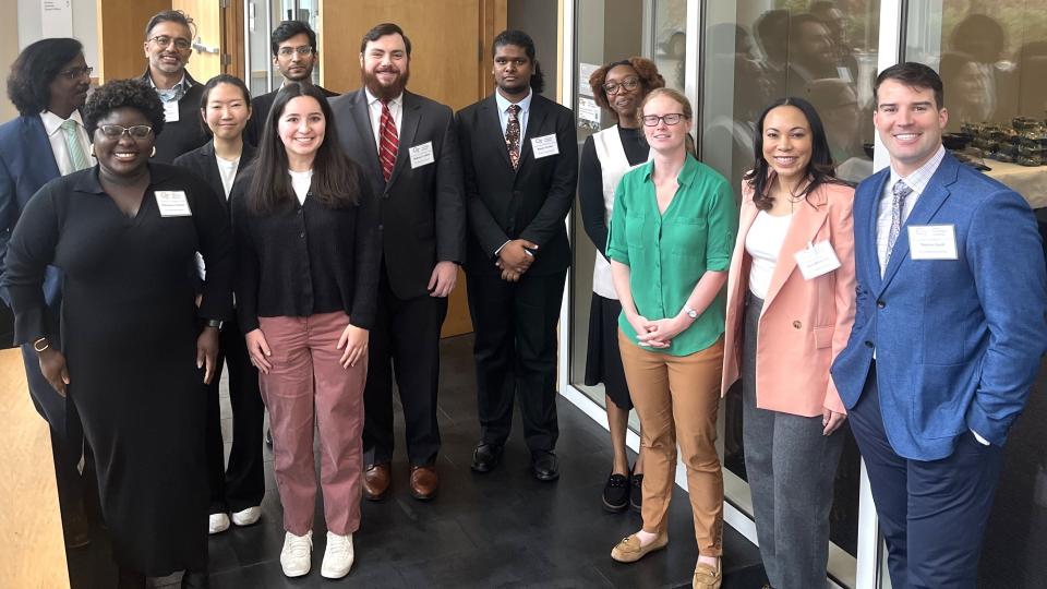 Group of Georgia Tech researchers and students standing indoors at a professional event, wearing business attire and conference name badges.