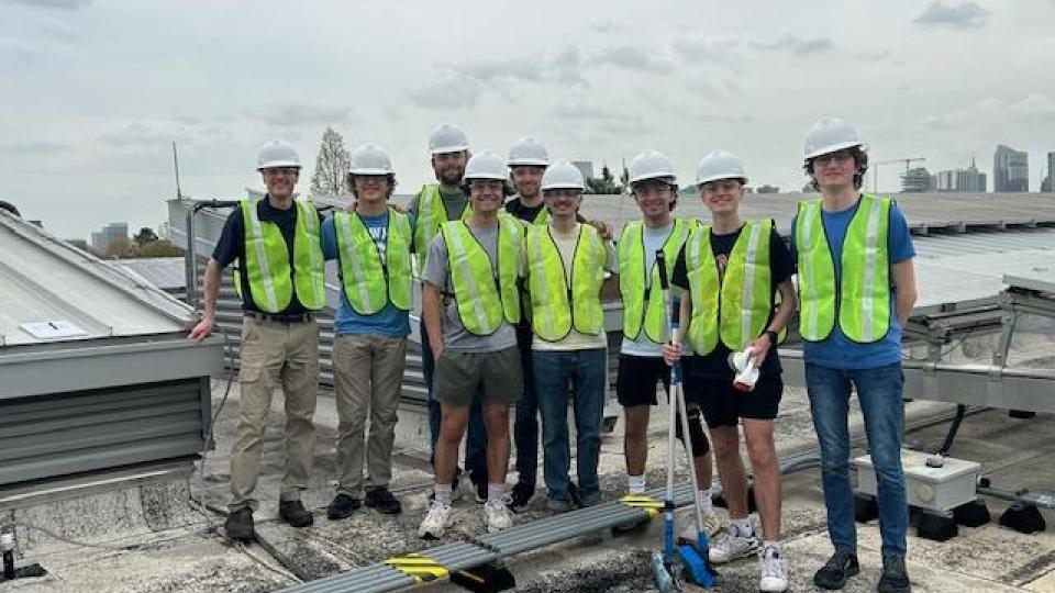 Georgia Tech Beautification Day volunteers on the rooftop of CNES building, with the cleaned solar panels in the background