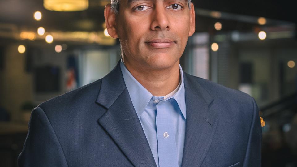 Karthik Ramachandran smiles in a navy suit coat