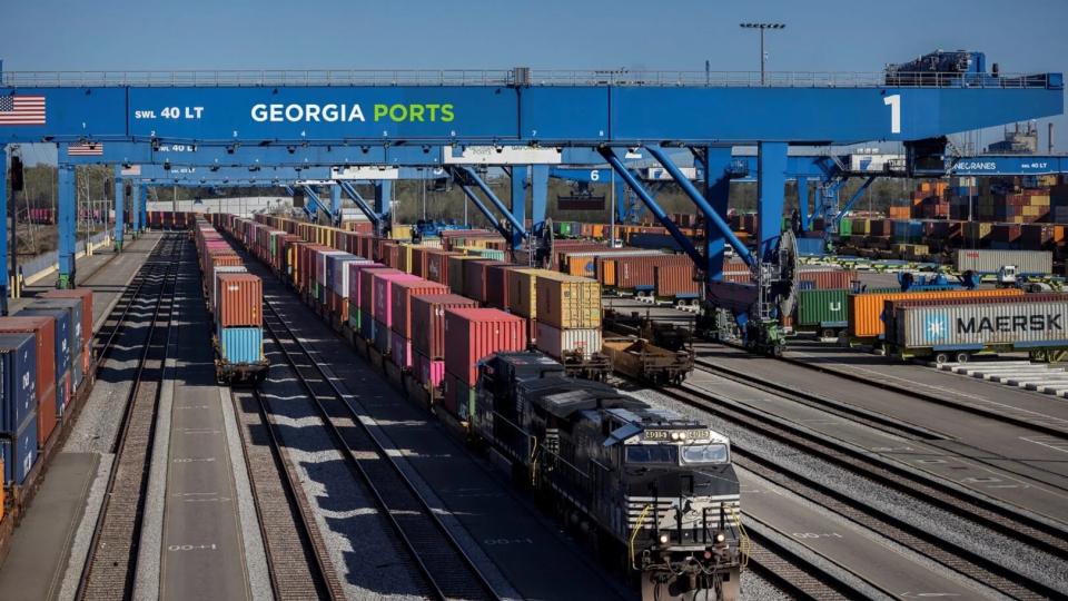 Railroad yard serving the Georgia Ports Authority with more than 6 railroad lanes with one engine towing a long line of intermodal containers.