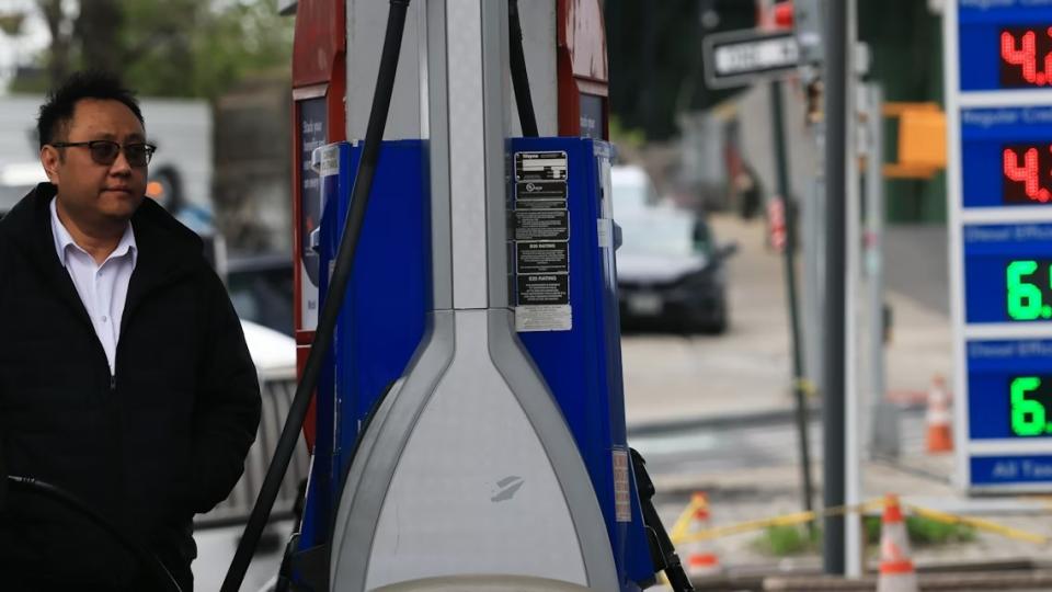 A person filling gas in his car with the gas prices shown in the foreground