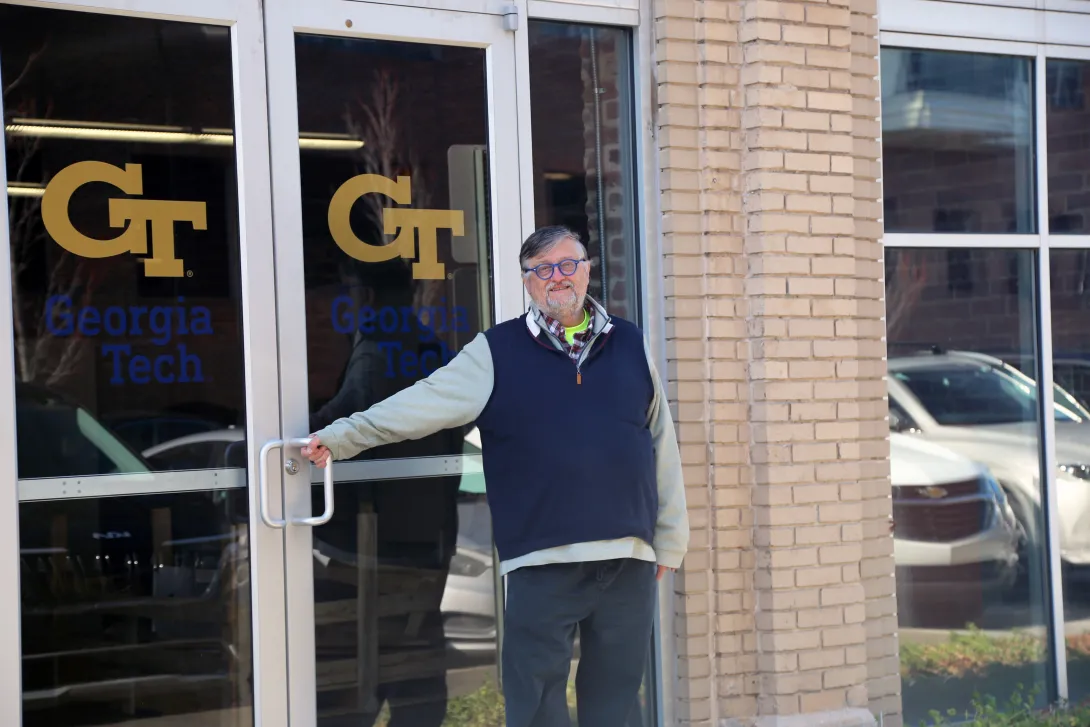 A man standing in front of glass double doors with the Georgia Tech logo.