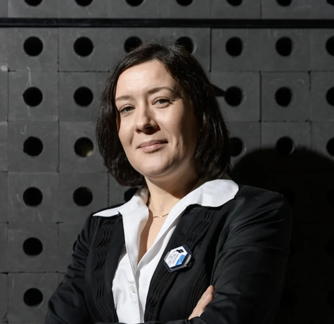 A woman with dark hair wearing a black blazer smiles