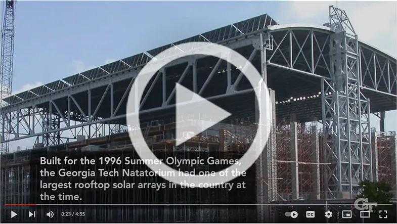 Image capture from the BBISS 30th Anniversary Video of the Georgia Tech Olympic Natatorium with a play button overlay.