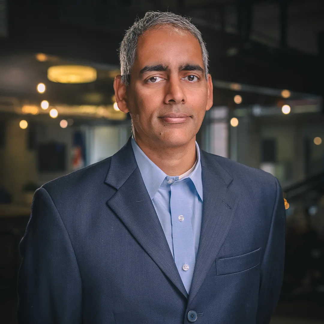 Karthik Ramachandran smiles in a navy suit coat