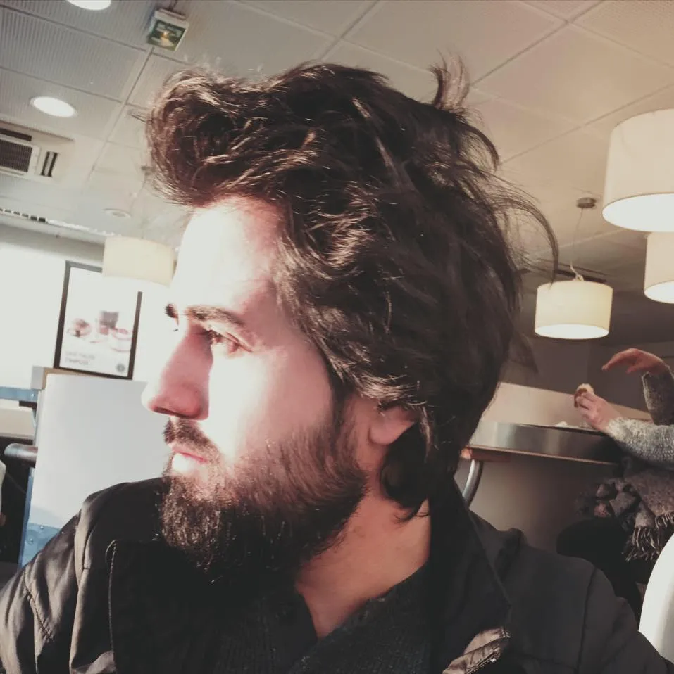 A side profile of a man's face. He has long hair and a beard
