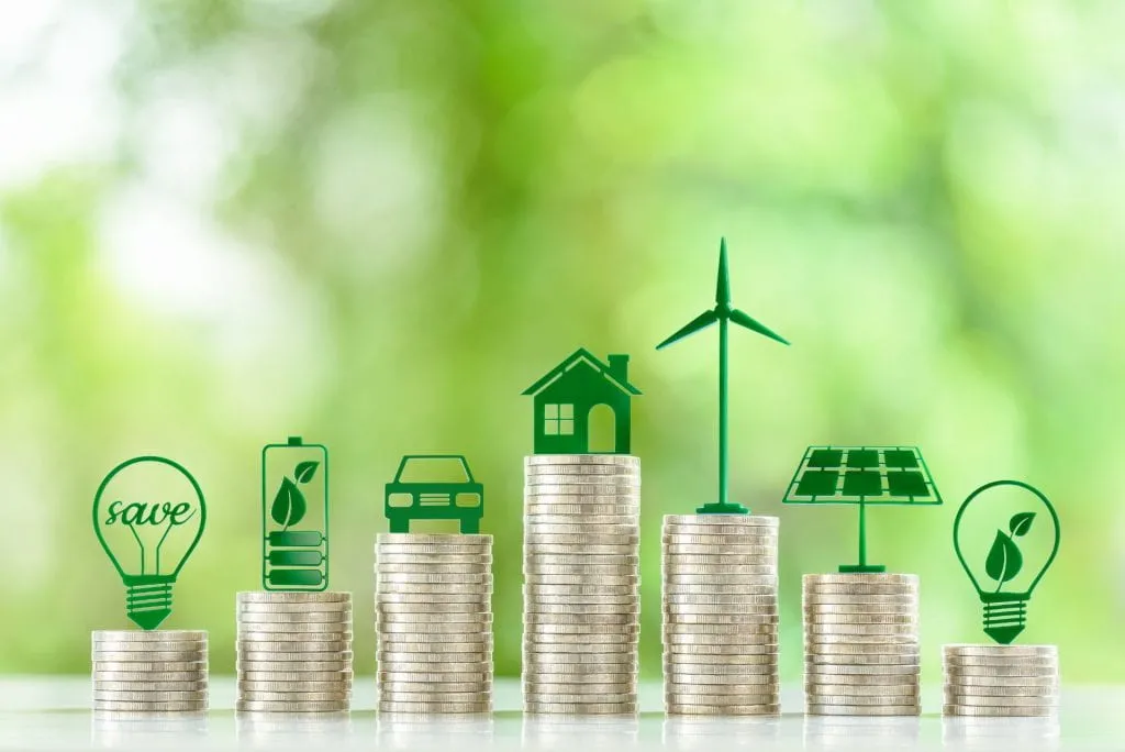 Stacks of coins topped with green icons representing clean energy and sustainability.